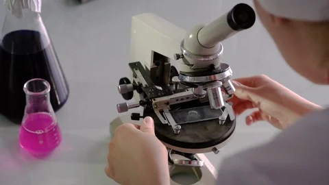 Close up laboratory assistant hand holding to adjust microscope in laboratory Stock Footage 74367681