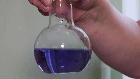 Close-up of a laboratory flask with purple liquid held by a scientist. Stock-Footage 329998350