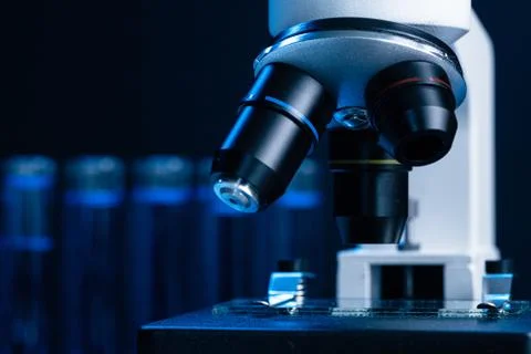Close up of laboratory microscope with set of test tubes with blue liquid Stock Photos