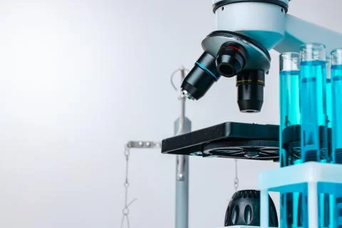 Close up of laboratory microscope with set of test tubes with blue liquid Stock Photos