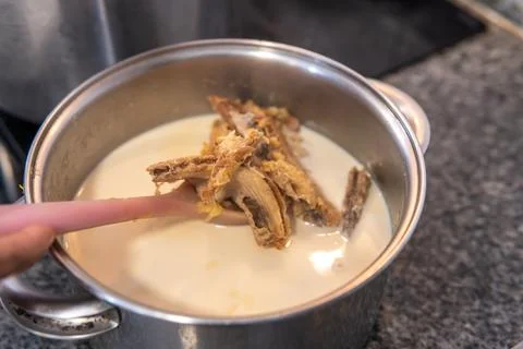 Close-up of a ladle taking out cod to remove the salt with milk Stock Photos