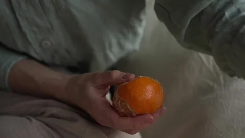 Close up lady hands claen orange mandarin relax sitting on pillow on the floor Video stock 254738006