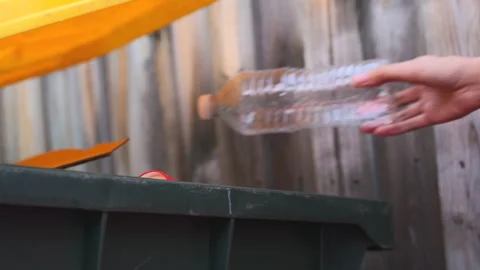 Close up lady throwing plastic bottle into yellow recycle bin container. 스톡 동영상 270411712