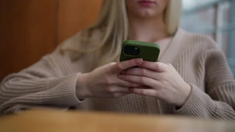 Close-up of lady using iphone with green case in casual setting Stock Footage 302264635