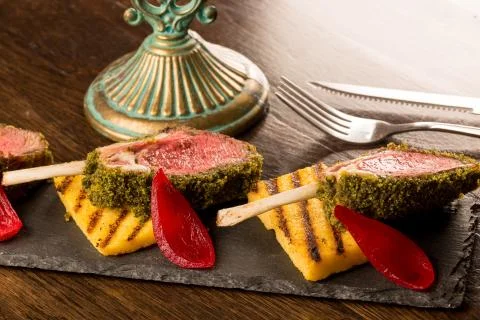 Close up of lamb chops with toasted bread and red onion on a black stone Stock Photos