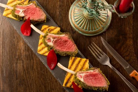 Close up of lamb chops with toasted bread and red onion on a black stone Stock Photos
