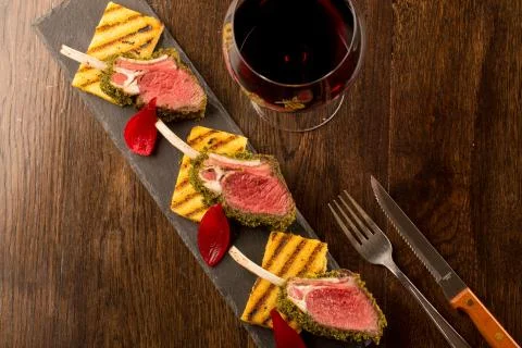 Close up of lamb chops with toasted bread and red onion on a black stone Stock Photos