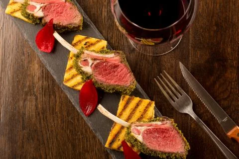 Close up of lamb chops with toasted bread and red onion on a black stone Stock Photos