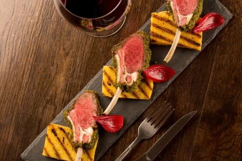 Close up of lamb chops with toasted bread and red onion on a black stone Stock Photos