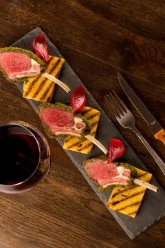 Close up of lamb chops with toasted bread and red onion on a black stone Foto stock