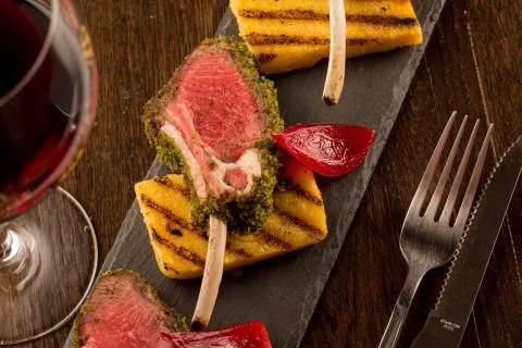 Close up of lamb chops with toasted bread and red onion on a black stone Stock Photos