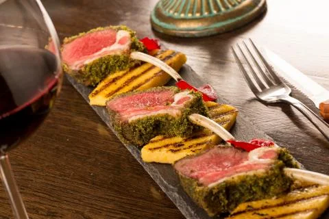Close up of lamb chops with toasted bread and red onion on a black stone Stock Photos