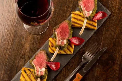 Close up of lamb chops with toasted bread and red onion on a black stone Stock Photos
