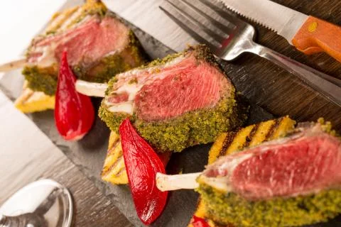 Close up of lamb chops with toasted bread and red onion on a black stone Stock Photos