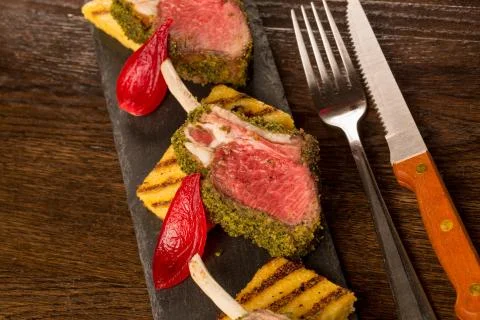 Close up of lamb chops with toasted bread and red onion on a black stone Stock Photos