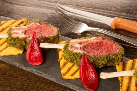 Close up of lamb chops with toasted bread and red onion on a black stone Stock Photos