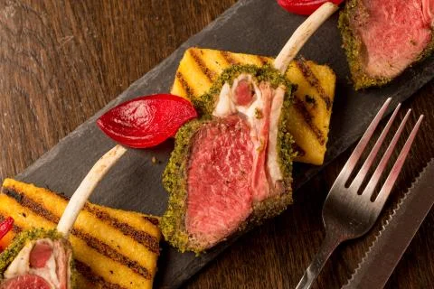 Close up of lamb chops with toasted bread and red onion on a black stone Stock Photos
