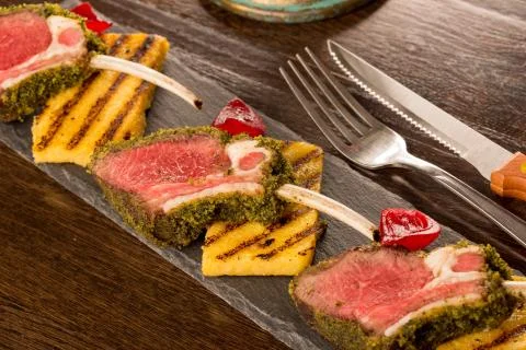 Close up of lamb chops with toasted bread and red onion on a black stone Stock Photos