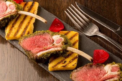 Close up of lamb chops with toasted bread and red onion on a black stone Stock Photos