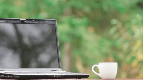 Close-up of a laptop and a white cup of coffee on a bench Video stock 80986251