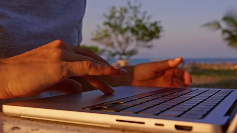 Close Up of Laptop Being Opened with Sunlight Glow and Tropical Background at Su Stock Footage 332304461