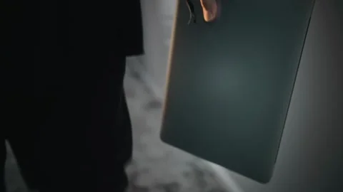 Close-up of a laptop in the hand of a man walking down a corridor. The computer Stock Footage 252274224
