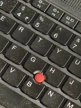 Close-up of a laptop keyboard featuring a red TrackPoint nub, used for cursor co Stock Photos