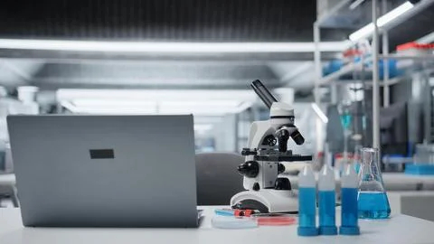 Close up of laptop on laboratory workbench next to microscope and samples Stock Photos