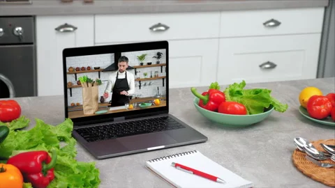 Close up laptop with man chef in screen tells removes vegetables from paper bag Video stock 155769979