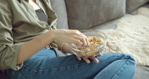 Close-up of a large bowl with popcorn in the hands of a woman watching a movie Stock Footage 130184005