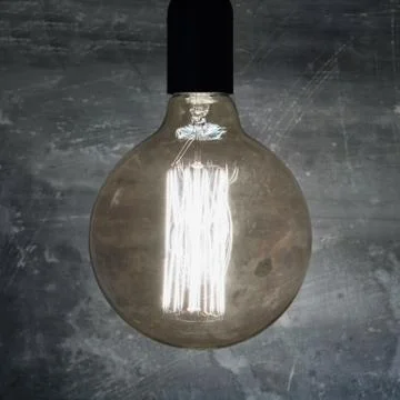 Close-up of a large burning retro light bulb. Concept of ideas and creativity. Stock Photos