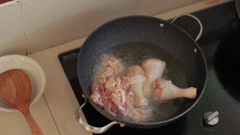 Close-up of a large deep frying pan and a hand of a man puts pieces of chicken Stock Footage 256614292