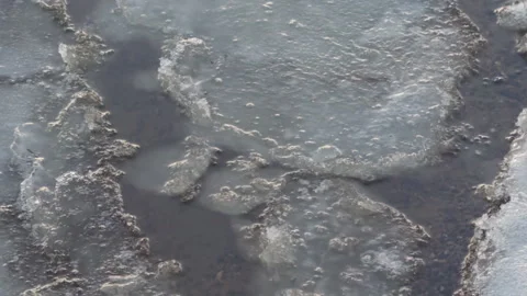 Close-up of large fragments of ice floes bobbing on the waves above the sandy Stock Footage 309018709