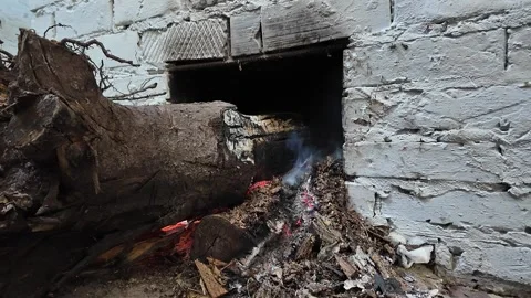 Close-up of a large log burning at the base of a rural fruit drying process. Stock Footage 328982090