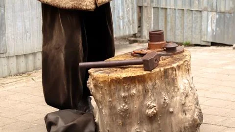 Close-up of a large old hammer lying on a tree stump anvil. Historical reen.. Stock-Fotos