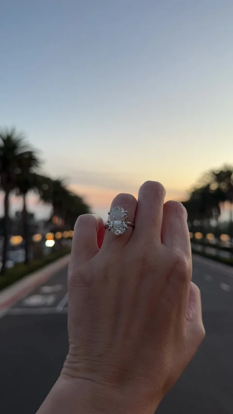 Close up large oval diamond solitaire engagement ring on hand at sunset Stock Footage 325876439