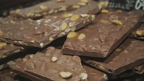 Close-up large pieces of chocolate with nuts on a shop window view through glass Stock Footage 136633524
