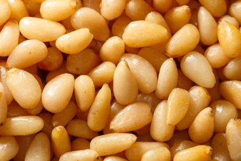 A close-up of a large pile of pine nuts. The nuts are mostly white with a s.. Foto stock