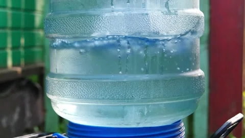 Close-up of large plastic water bottle filling a barrel outdorrs Stock Footage 201216360