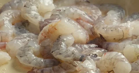Close up of large raw shrimp sizzling while being pan fried in a hot skillet. Vidéo 339335578