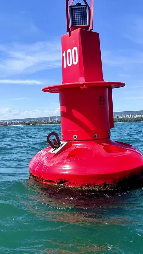 A close-up of a large red buoy with the number "100," floating on the ocean Stock Footage 298023168
