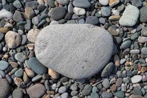Close-up of a large rounded stone against a background of natural pebbles. Top Stock Photos