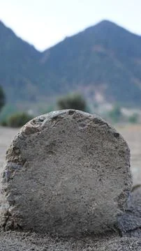 Close-up of a large weathered gray stone boulder, hazy mountain landscape. Stock Photos