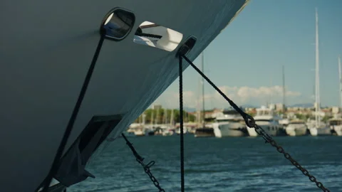 Close up of a large yacht bow with mooring ropes and chains, with sailboats and Stock Footage 339765083