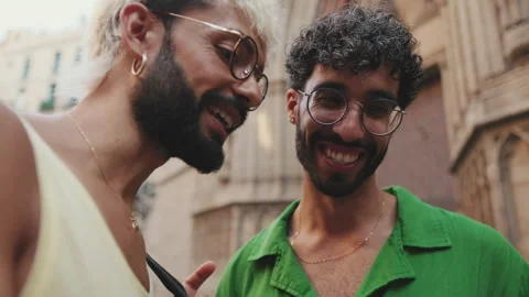 Close-up, laughing homosexual couple using mobile phone while standing on street Stock Footage 255505124