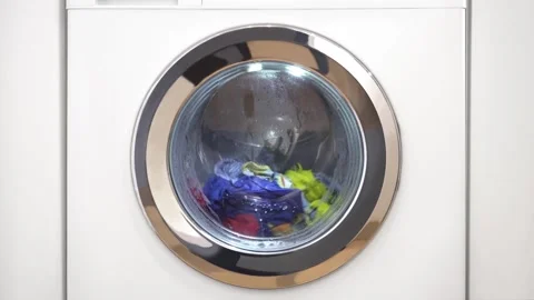 Close up laundry machine spinning washing clothing bubbling water house life Stock Footage 336563748
