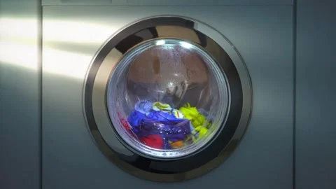 Close up laundry machine spinning washing clothing bubbling water house life Stock Footage 336563772