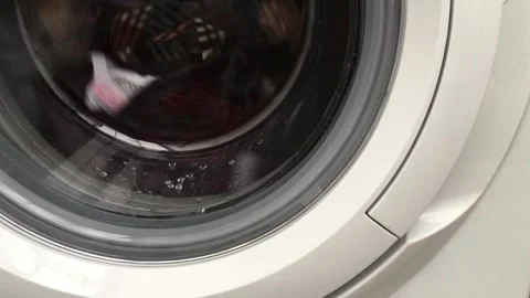 Close up laundry machine spinning washing clothing bubbling water house life Stock Footage 336594466