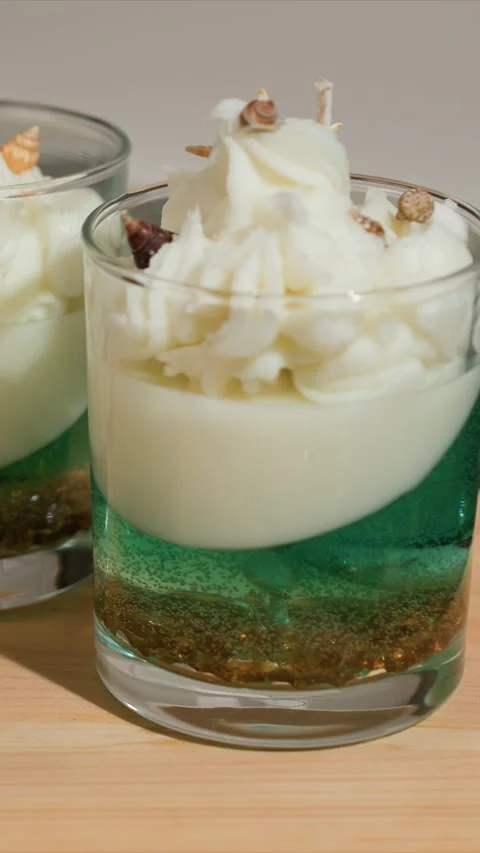 Close up of layered candles in glass with seashell toppers on wooden surface Vídeo Stock 344677489