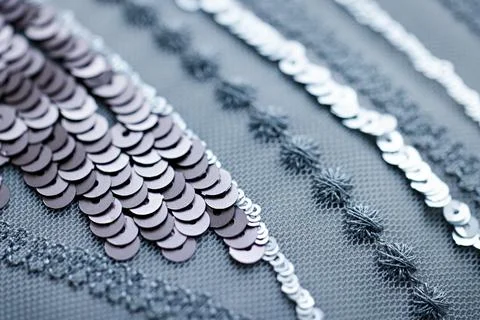 Close-up of layered silver sequins on dark blue fabric with fine embroidery.. Stock Photos